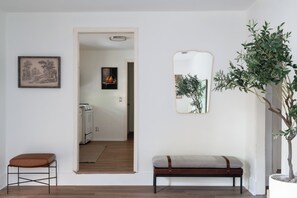 A hallway with a bench, a framed picture, a mirror, and a potted plant. - SoCo Central Stylish 4BR with Renovated Baths (Austin)