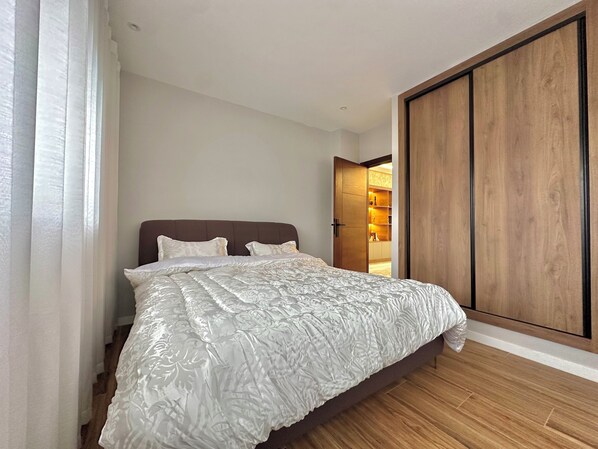 Une chambre avec un grand lit, une armoire en bois et une bibliothèque intégrée.