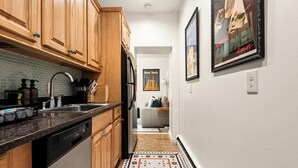 A kitchen with wooden cabinets, a dishwasher, and a tiled backsplash. - NEW - Stylish Art Deco Apt • Easy Access to Manhattan (Hoboken)