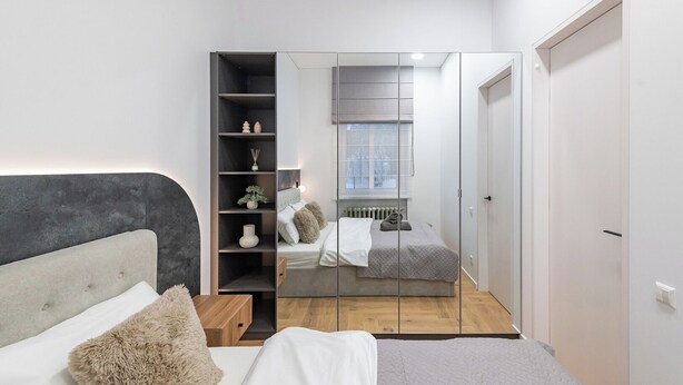 A modern bedroom with a bed, a built-in wardrobe, and a window. - Vytauto 43 Residence – Lietūkis by Domvia (Kaunas)