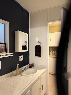 A bathroom with a white sink, a mirror, and a towel rack. - Hit the Trail or Lake: Spacious 4BR/2BA Retreat with Pool Table & Large Bar Area (Needles)