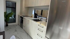 A modern kitchen with light wood cabinets, a stainless steel refrigerator, and a marble floor. - Central 2BR Townhouse with Private Yard (Christchurch)