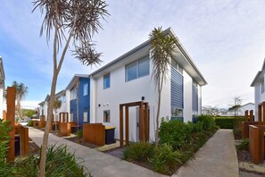 Un edificio residencial moderno con techo plano, ventanas amplias y entrada protegida por una reja.
