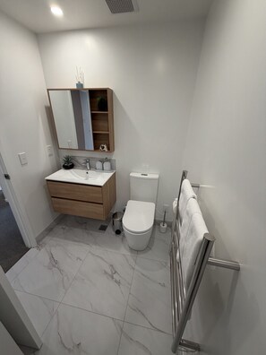 Een kleine badkamer met een wit wastafel, spiegel en toilet.