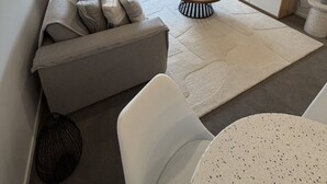 Ett modernt vardagsrum med en grå soffa, ett soffbord och en platt-TV.