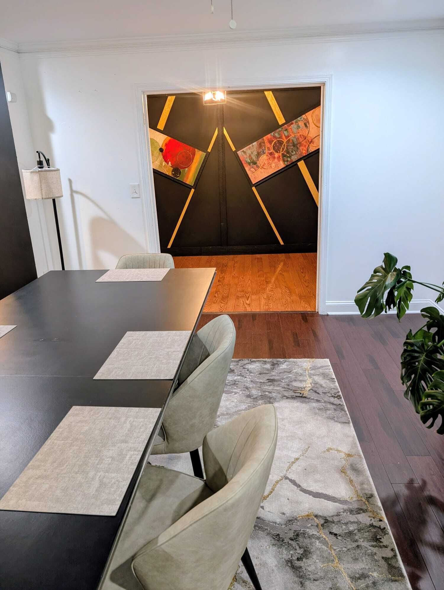 Ein Konferenzraum mit langem Tisch, Stühlen, einem gemusterten Teppich und einer Wand mit abstrakter Kunst.