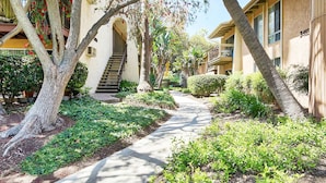 A pathway leading to a building with a staircase, surrounded by greenery and trees. - Disneyland Days, Surf City Waves, Newport Nights (Costa Mesa)