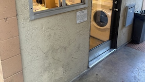 A laundromat with a glass door, a sign warning about a proposal, and a view of the interior with washing machines and dryers. - Disneyland Days, Surf City Waves, Newport Nights (Costa Mesa)