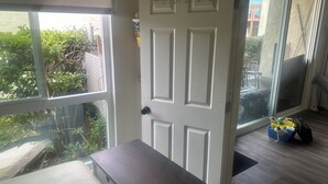 A room with a large window, a door with a metal hook, and a small table. - Disneyland Days, Surf City Waves, Newport Nights (Costa Mesa)