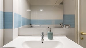 Ein Badezimmer mit einem weißen Waschbecken, einem Spiegel und einer Dusche.