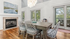 A dining area with a fireplace, wooden dining table, and chairs. - Pet friendly home located in the middle on Bald Head Island (Bald Head Island)