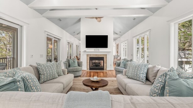 A modern living room with a fireplace, sofas, and a television. - Pet friendly home located in the middle on Bald Head Island (Bald Head Island)