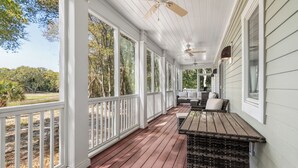 A covered porch with white railings, a wooden table, and outdoor seating. - Pet friendly home located in the middle on Bald Head Island (Bald Head Island)