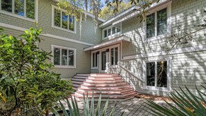 A two-story house with a brick exterior, a front porch, and a set of stairs leading to the entrance. - Pet friendly home located in the middle on Bald Head Island (Bald Head Island)