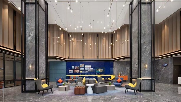 Un hall d’entrée spacieux avec un espace salon central, de hauts plafonds et un éclairage moderne.