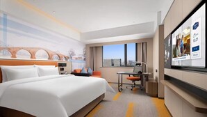 Une chambre d’hôtel avec un grand lit, un bureau, une chaise, une télévision et une fenêtre donnant sur la ville.