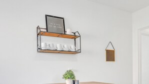 A rustic wooden table with a bench, a metal shelf with white cups, and a framed quote on the wall. - 5Min to Downtown Franklin/Pet Friendly/Fenced Yard (Franklin)