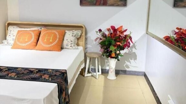 Ein Schlafzimmer mit einem Bett, einem Nachttisch, einer Topfpflanze und einem Bild an der Wand.