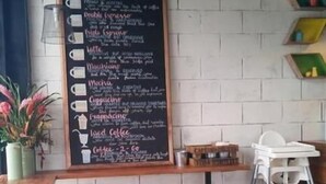 Ein Café-Interieur mit einer Kreidetafel, bunten Hocker und einem weißen Hochstuhl.