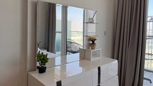 Un bagno moderno con uno specchio grande, un mobile bagno bianco, una pianta in vaso e vista sull'esterno attraverso un'ampia finestra.