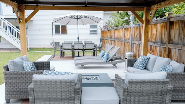 Une terrasse extérieure aménagée avec des meubles en osier, une table et un parasol.