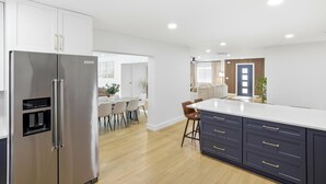 Eine moderne Küche mit einem Edelstahl-Kühlschrank, einer weißen Arbeitsplatte und dunkelblauen Schränken.