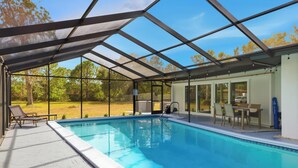 Ein überdachter Pool mit einer Terrassenfläche, einem Tisch und Stühlen.