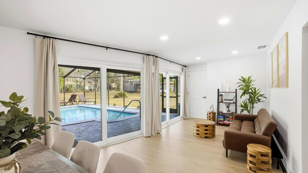 Ein modernes Wohnzimmer mit Blick auf einen Pool, einer Couch und einem Essbereich.
