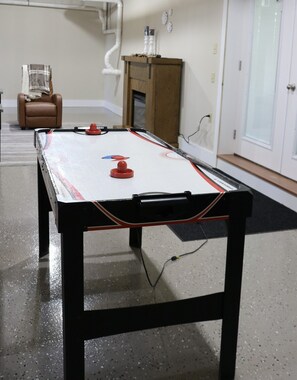 A pool table in a room with a brown leather chair, a wooden cabinet, and a white door.