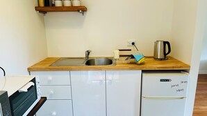 Pieni, käytännöllinen keittiö, jossa on pesuallas, vedenkeitin, mikroaaltouuni ja jääkaappi.