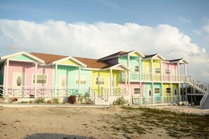 A multi-story building with a flat roof, a balcony on the second floor, and a staircase leading to the upper levels. - Quaint 1-bedroom villa with AC in charming Rolleville Exuma Bahamas (Rolleville)