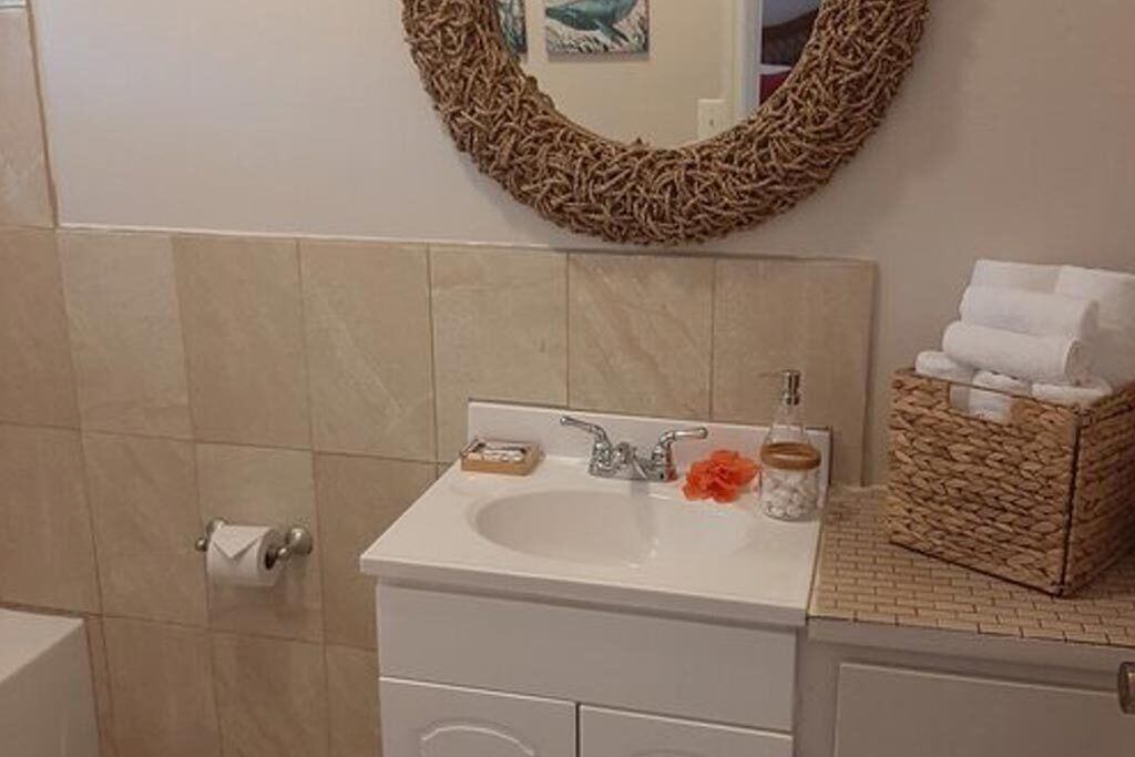 A bathroom with a white sink, a mirror, and a wicker basket on the countertop.