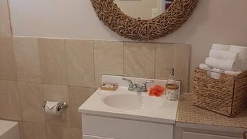 A bathroom with a white sink, a mirror, and a wicker basket on the countertop.