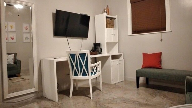Habitació amb escriptori, cadira, televisió i sofà.