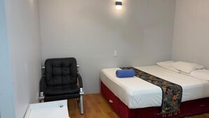 Una stanza piccola e funzionale con un letto singolo, una sedia e una scrivania.