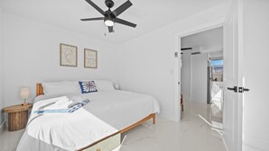 A bedroom with a bed, a nightstand, a ceiling fan, and two wall art pieces.
