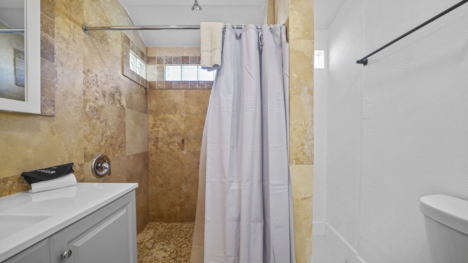 A bathroom with a shower, a sink, and a toilet.