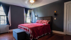 Un dormitorio con una cama grande, una mesita de noche, una lámpara y una ventana con cortinas.