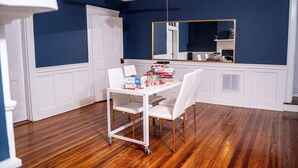 Una habitación con una mesa y sillas blancas, un ventilador de techo y un espejo grande en la pared.
