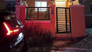 A residential building with a gated entrance, a car parked in front, and a visible house number.