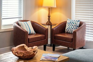 Two leather armchairs with decorative pillows, a small wooden table with magazines, and a lamp between them. - Only 3 minutes walk to beach - Spacious Destin Home, Newly-renovated (Destin)