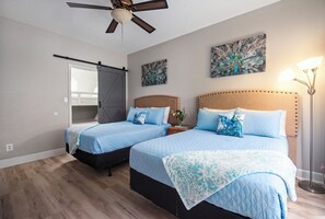 A bedroom with two beds, a ceiling fan, and artwork on the walls. - Only 3 minutes walk to beach - Spacious Destin Home, Newly-renovated (Destin)