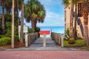 A pathway leading to a building with a red roof, surrounded by palm trees and a view of the sea. - Only 3 minutes walk to beach - Spacious Destin Home, Newly-renovated (Destin)