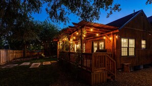 A wooden cabin with a porch, string lights, and a fenced yard. - Whitewater Lodge-4units*nearDT (Boise)