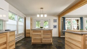 A modern kitchen with wooden cabinets, a central island, and a stone floor. - Whitewater Lodge-4units*nearDT (Boise)
