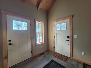 A hallway with two white doors, a window, and a doormat. - 4 Bed Luxury White Mtn Retreat w/ Stunning Views! (Campton, NH)
