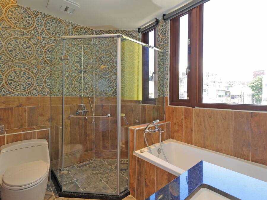 A bathroom with a glass shower enclosure, a bathtub, and a toilet.
