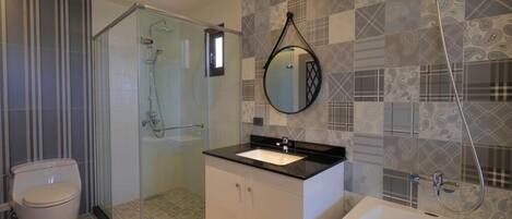 A modern bathroom with a glass-enclosed shower, a white sink, and patterned tiles.