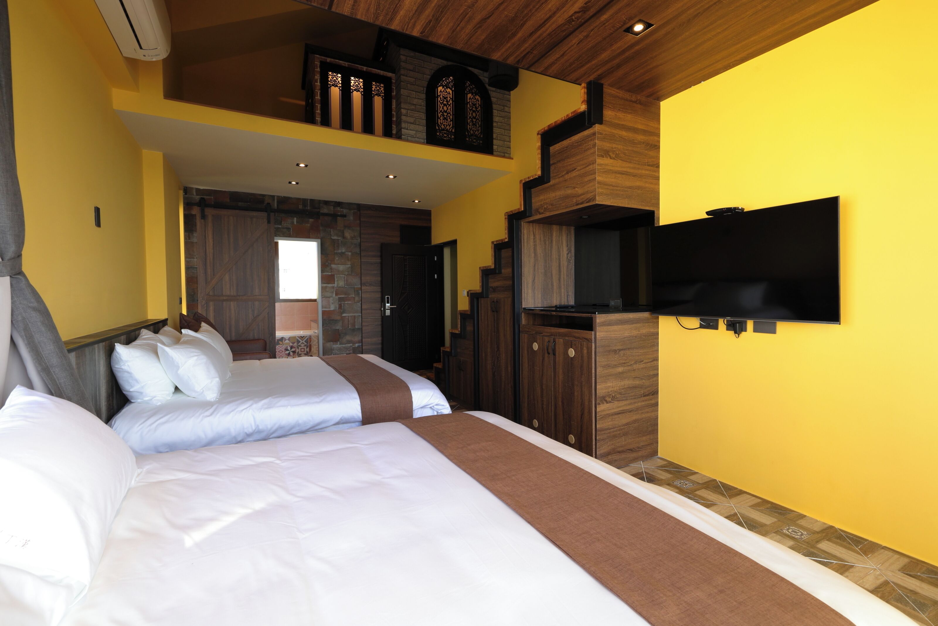 A hotel room with a large bed, a TV mounted on the wall, and a wooden ceiling.