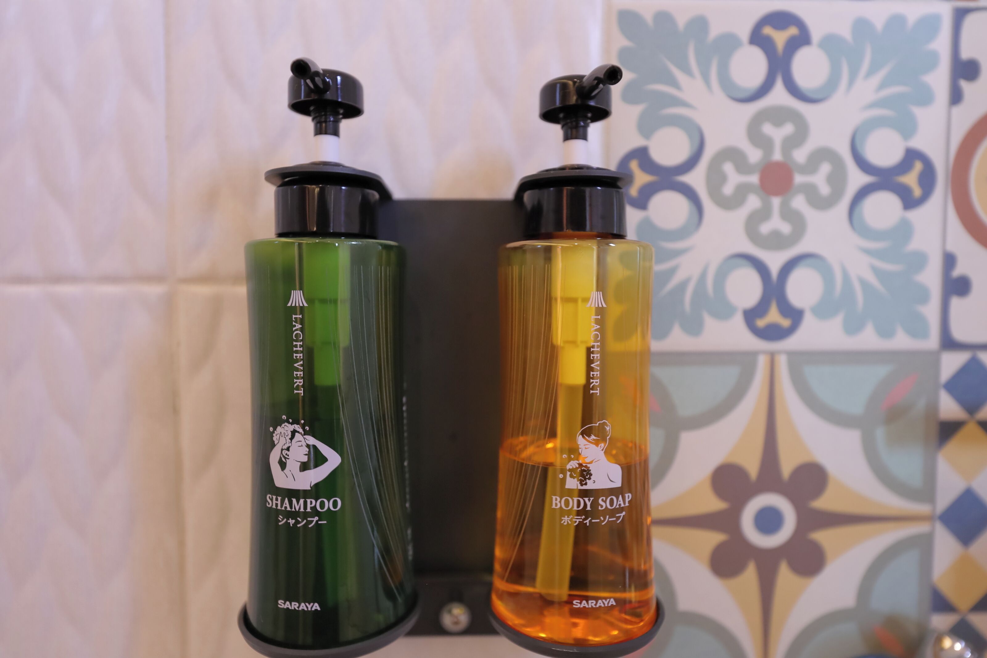 Hyllyllä on kaksi pulloa shampoota ja nestesaippuaa.